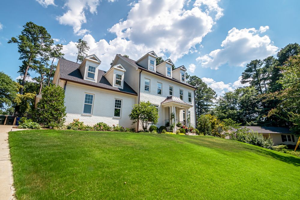 White colonial home on a hill with a lush, healthy green lawn