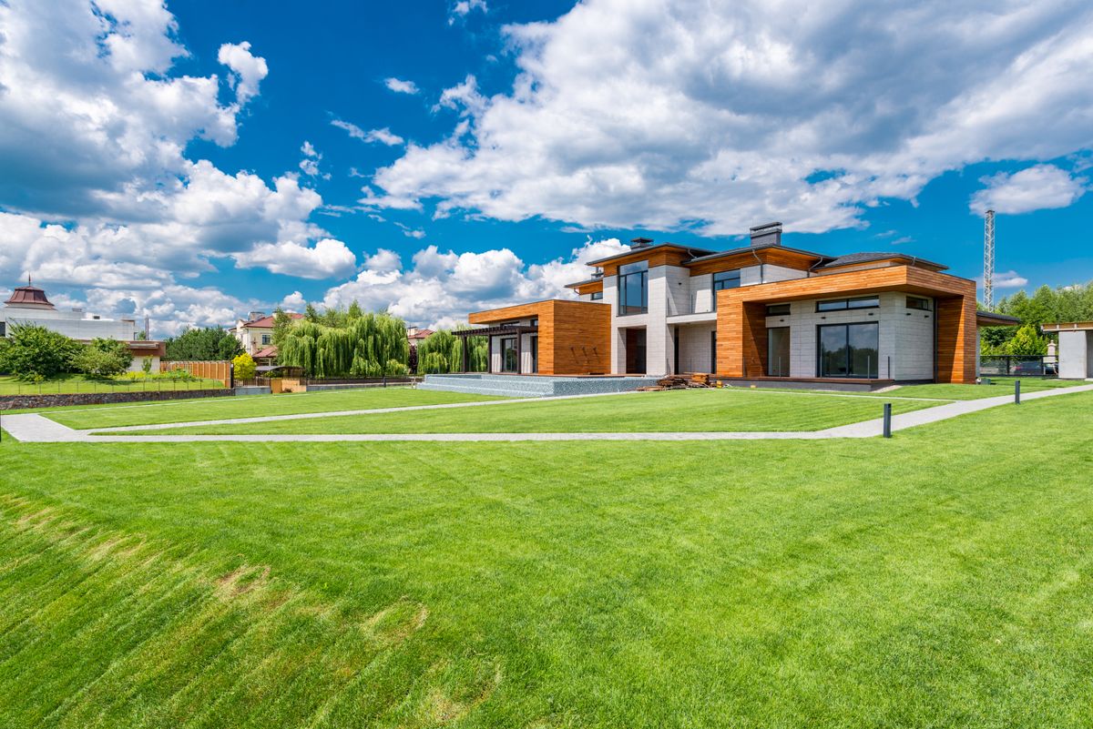 Sprawling manicured lawn in front of a modern home under a blue sky