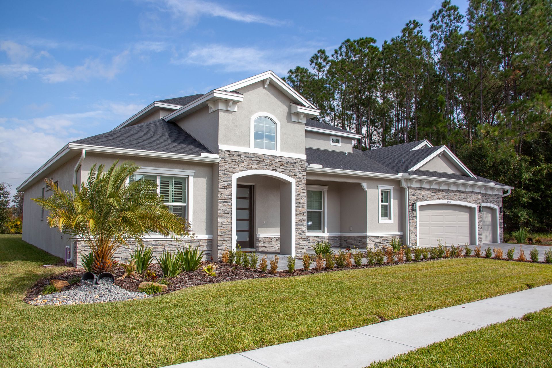 A Florida home with stone accents, a palm tree, and a lush, freshly mowed green front lawn