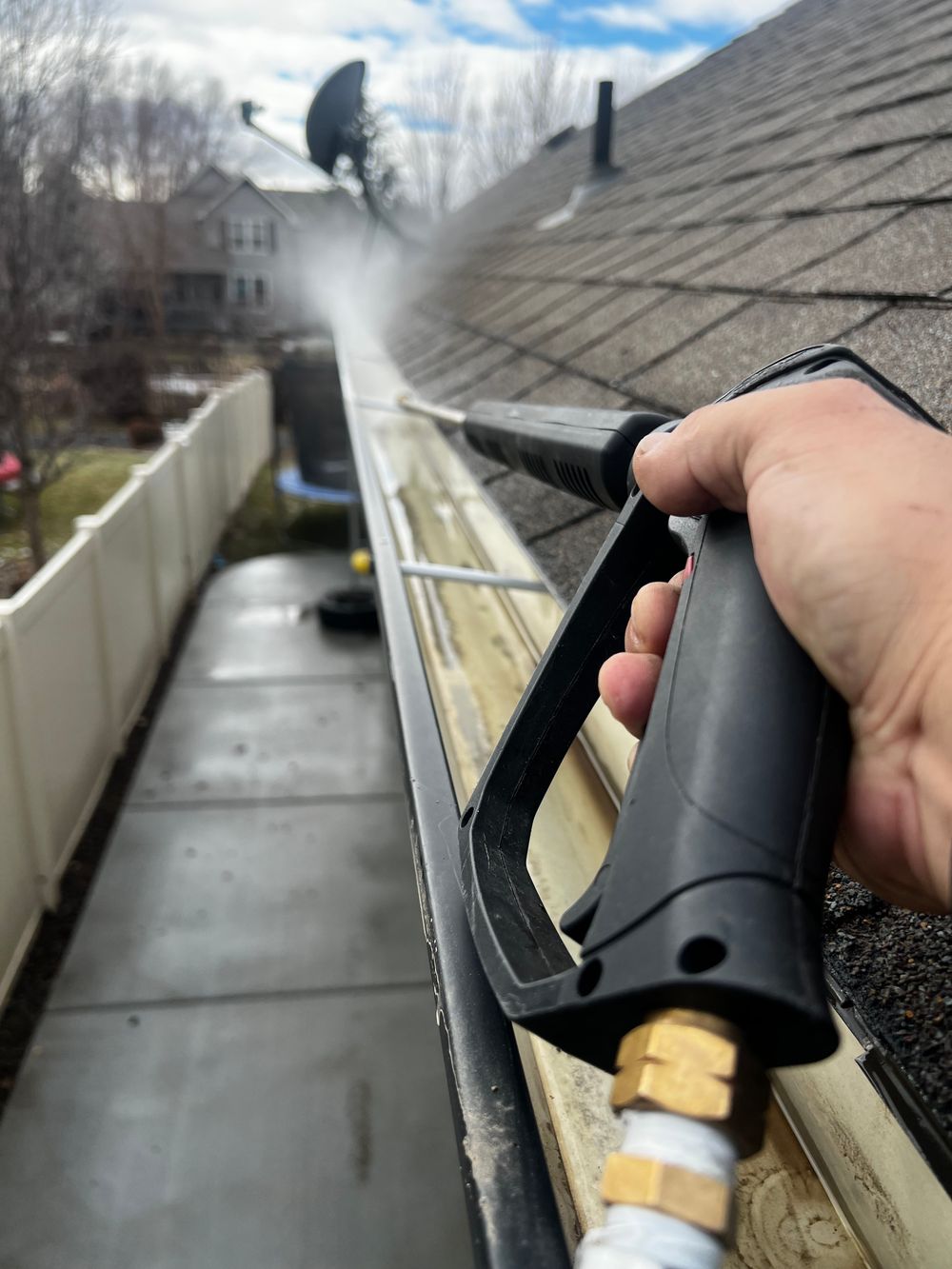 Clearing leaves and debris from a home's gutter with a pressure washer