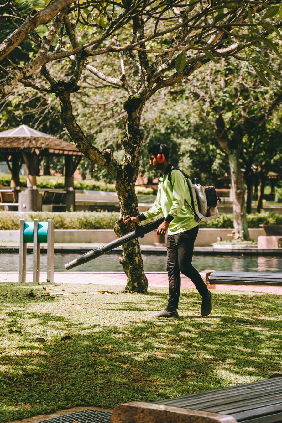 Worker using a backpack leaf blower to clear debris from a lawn